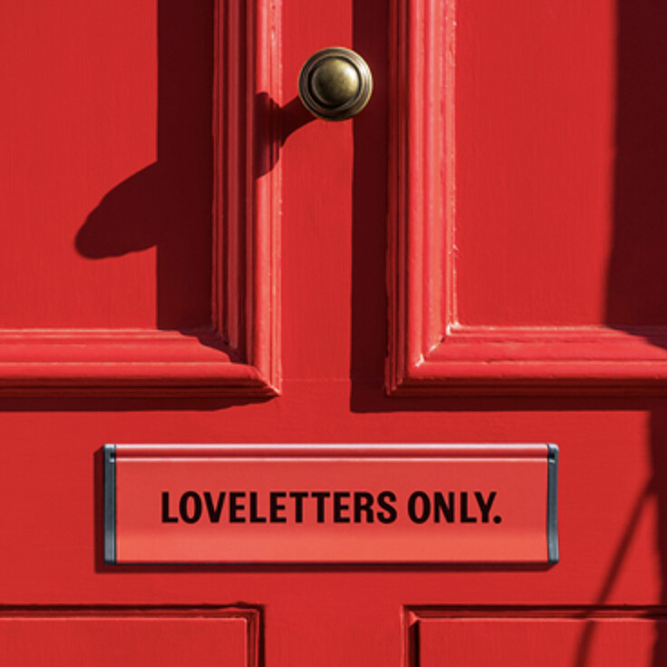 Red door with mail slot reading loveletters only